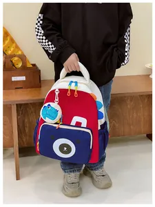 Detail of cute dinosaur pendant and bear print on kids nylon backpack for school