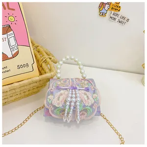 Detail of floral embroidery mini bag with pearl handle and elegant hanging tassels