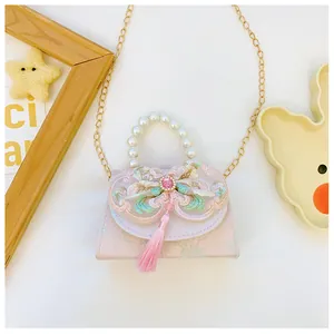 Close-up of pink silk kids handbag with floral embroidery, pearl handle and gemstone tassel