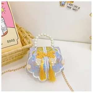 Detail of floral embroidery, pearl handle, and golden chain on girl's vintage bag