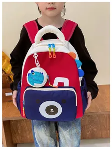 Detail of red and blue kids backpack with cartoon bear face and dinosaur pouch accessory