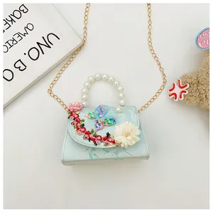 Détail d'un sac à main enfant bleu clair avec broderie florale et anse en perles