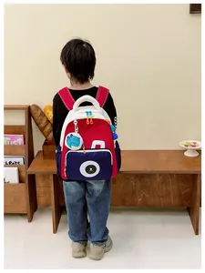 Detailed back view of a colorful dinosaur toddler backpack with bear print in a cozy setting