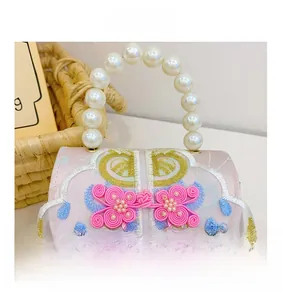 Close-up of pink silk embroidery bag with pearl handle, floral patterns and silk tassels