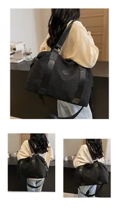 Close-up of black quilted travel tote bag with textured fabric and wide nylon strap