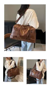 Detail einer großen braunen Reisetasche mit N-Prägung und breitem Schultergurt-Design