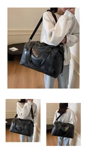 Detailansicht der schwarzen Reisetasche aus strukturiertem Kunstleder mit Logo und Gurt