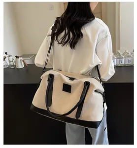 Detail of canvas travel tote featuring black leather trim and adjustable shoulder strap
