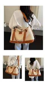 Detail of canvas travel bag with brown leather handles and adjustable shoulder strap