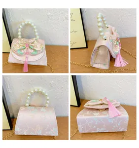 Detail of pink floral handbag for kids with pearl handle, embroidery, and long tassels