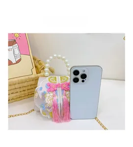 Macro detail of Chinese embroidery bag next to a smartphone showing small compact size