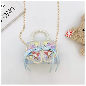 Close-up of light blue kids bag with floral embroidery, pearl handle and silk bow detail