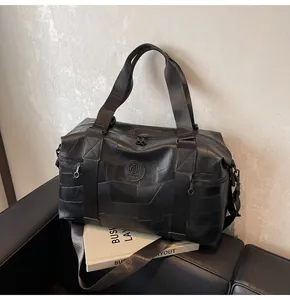 Detaillierte Nahaufnahme einer großen schwarzen Reisetasche mit Logo auf einem Ledersofa