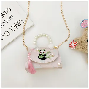 Détail de la broderie panda avec poignée en perles et pompon rose sur un sac fille