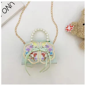 Detail of mint green girl's bag with pearl handle, floral embroidery and metal chain