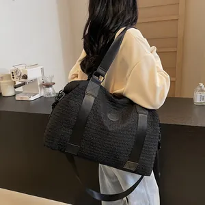 Detail of black large capacity shoulder bag with pleated texture and embossed round logo