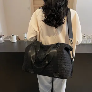 Detail of black large travel bag showing textured bubble fabric and wide shoulder strap