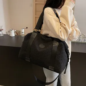 Large black travel bag with pleated texture and round logo shown on a shoulder