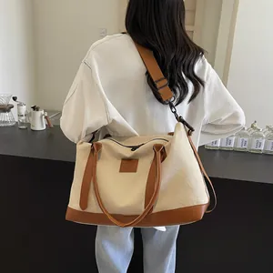 Rear view of model carrying large canvas and brown leather travel tote in a cafe setting