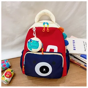 Detail of red and blue kids dinosaur backpack with cute bear print and round charm
