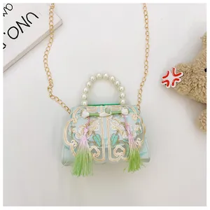 Detail of floral embroidery, traditional tassel, and pearl handle on blue handbag