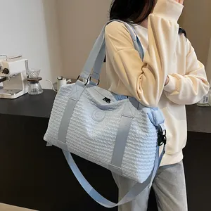 Detail of light blue travel bag featuring wavy textured fabric and top handle straps