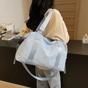 Detailed side view of a light blue quilted travel bag worn by a model in a cafe