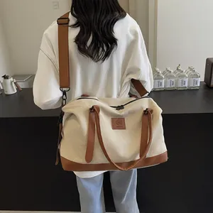 Detail of canvas and leather tote bag featuring adjustable strap and leather logo patch