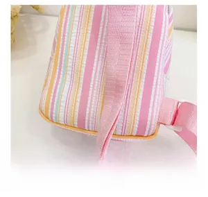 Detail of colorful striped shoulder bag showing soft pink strap and white plastic buckle