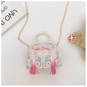 Detail of pink embroidered handbag with pearl handle and traditional tassels
