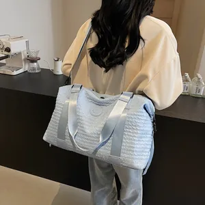 Close-up of light blue quilted travel bag showing waterproof fabric and wide shoulder strap