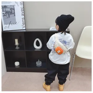 Detail of child wearing a beige canvas crossbody bag with orange coin purse on back