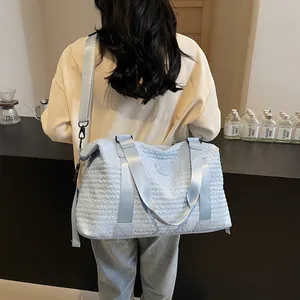 Detail of light blue waffle-textured travel bag showing dual straps and round logo embossed
