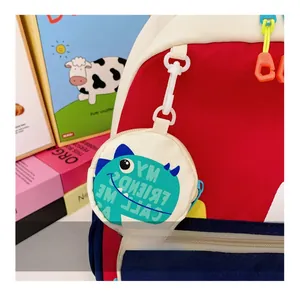 Close-up of a round coin purse featuring a cartoon dinosaur print on a kids' backpack