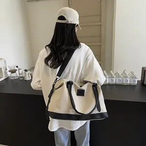Rear view of a beige canvas tote bag with black leather trim and dual carrying straps