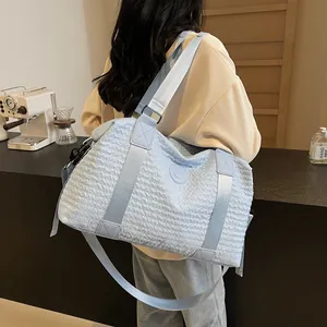 Close-up of light blue travel bag featuring wavy quilted texture and nylon strap
