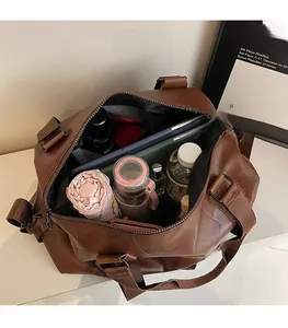 Geräumiges Innenleben der braunen Kunstleder-Reisetasche mit Schirm, Flasche und Tablet