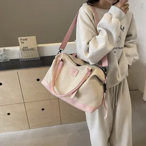 Close-up of cream and pink canvas travel bag with adjustable strap on a female model