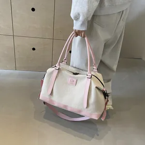 Detail of canvas travel bag with pink leather handles and branded logo patch