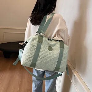 Close-up of mint green travel bag featuring unique pleated texture and shoulder strap