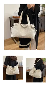 Dettaglio di una grande borsa da viaggio beige con opzioni di trasporto a mano e a spalla