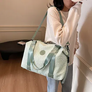 Detail of mint green travel bag featuring unique pleated texture and adjustable strap