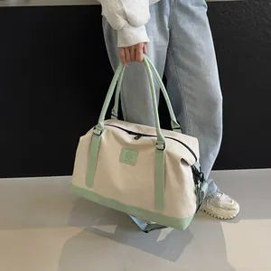 Close-up of canvas travel bag with mint green leather trim and adjustable strap