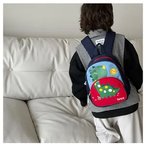 Vista posteriore di un bambino con lo zaino da dinosauro blu su sfondo divano bianco