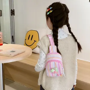 Cute striped children crossbody bag with 3D cherry decor on a girl in a cozy cafe