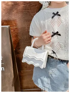 Gros plan sur le sac enfant blanc avec rabat ondulé et logo de KAYINAI