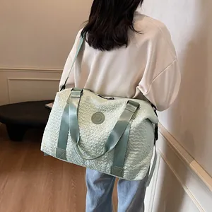 Close-up of light green travel bag with pleated texture and adjustable shoulder strap