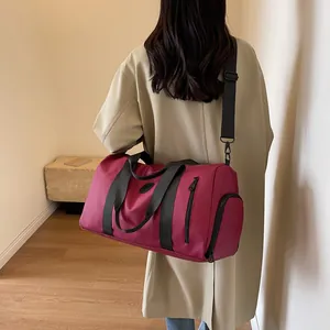 Detail of burgundy waterproof duffel bag with a separate shoe compartment and shoulder strap