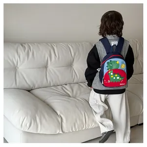 Dettaglio dello zaino per bambini con dinosauro e tasca frontale rossa per la scuola