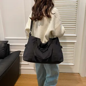 Modella indossa una borsa da viaggio in nylon nero con tracolla in un interno moderno